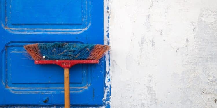 red and orange push boroom leaned on blue door