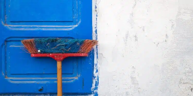 red and orange push boroom leaned on blue door