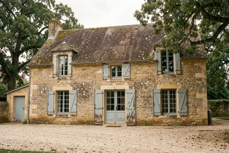 Façade d'une ancienne maison en pierre calcaire en milieu rural français, montrant les joints de mortier et la patine naturelle du bâti ancien