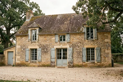 Façade d'une ancienne maison en pierre calcaire en milieu rural français, montrant les joints de mortier et la patine naturelle du bâti ancien